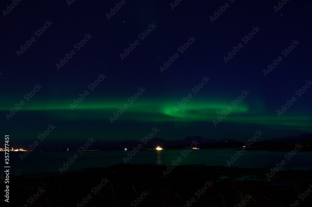 beautiful aurora borealis over fjord and land in tromsoe