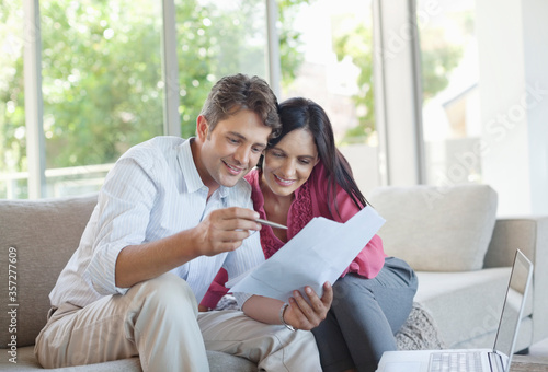Couple reading papers together on sofa