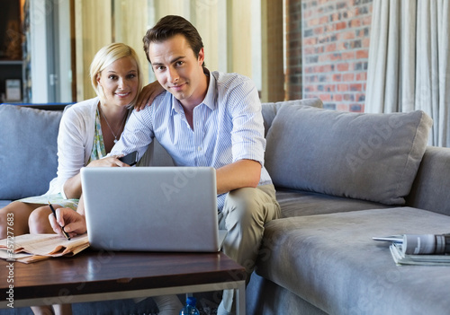 Couple using laptop together on sofa