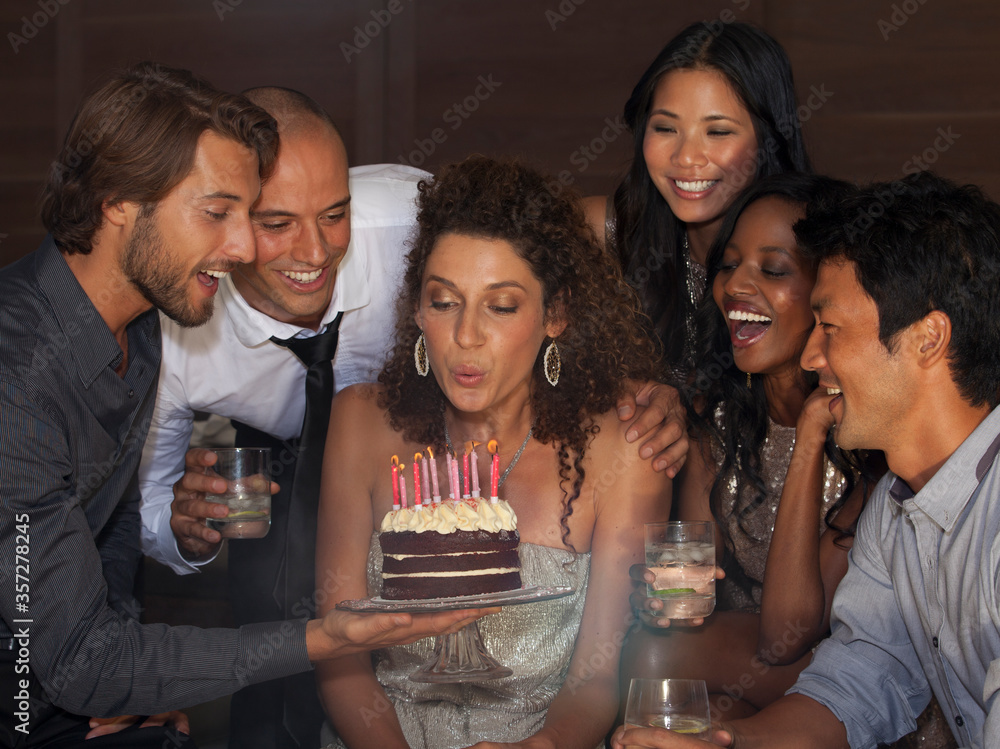 Woman blowing out birthday candles at party