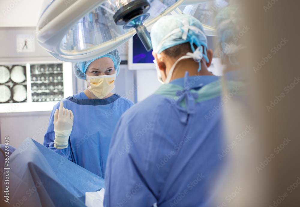 Surgeons standing over patient in operating room Surgeons standing over patient in operating room