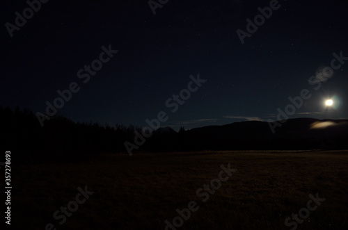 full moon over field and mountain in autumn night