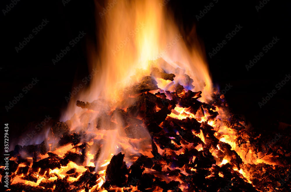 beautiful red hot glowing ember pile with colorful flames in winter night beautiful red hot glowing ember pile with colorful flames in winter night