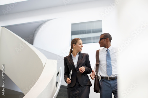 Konstfotografi Businessman and businesswoman talking on modern staircase