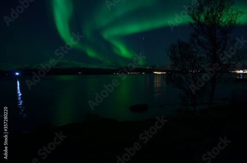 fantastic strong aurora borealis over cold fjord and mountain