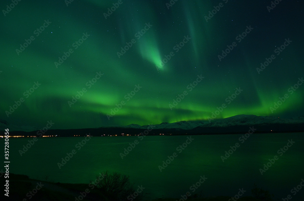insanly strong aurora borealis over arctic fjord and mountain landscape