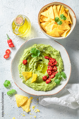 Fresh guacamole with nachos, chilli peppers and coriander