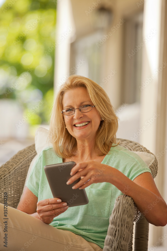 Portrait of smiling woman using digital tablet on porch