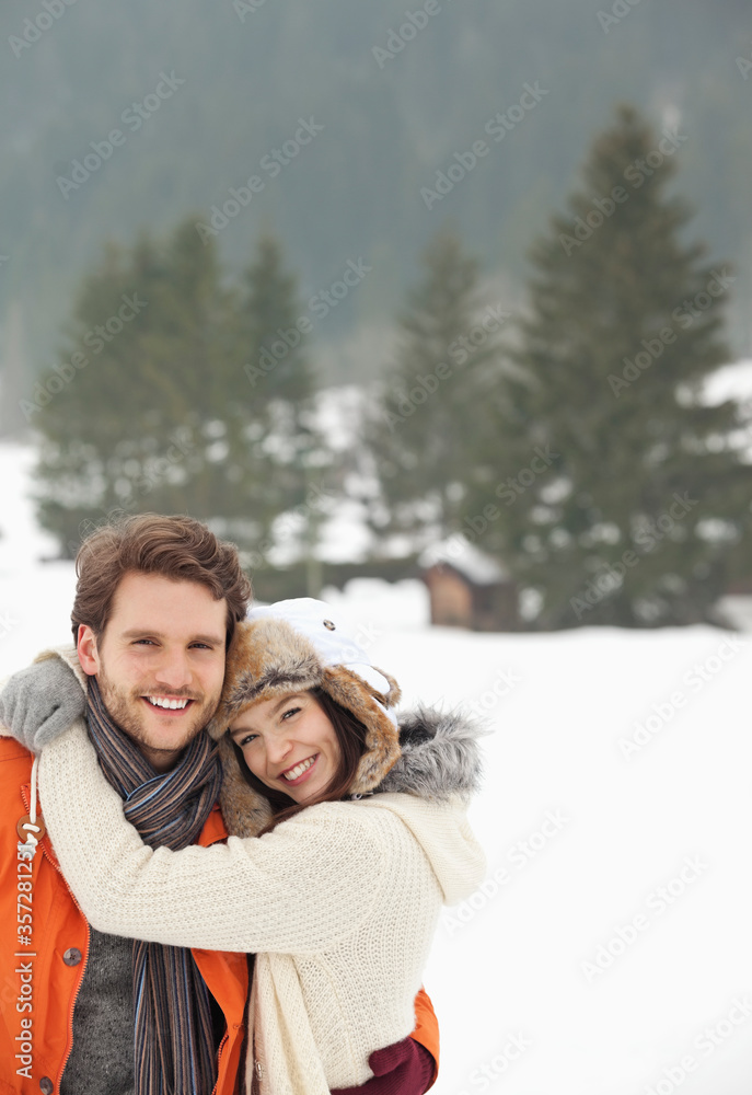 Portrait of smiling couple hugging in snowy field Portrait of smiling couple hugging in snowy field