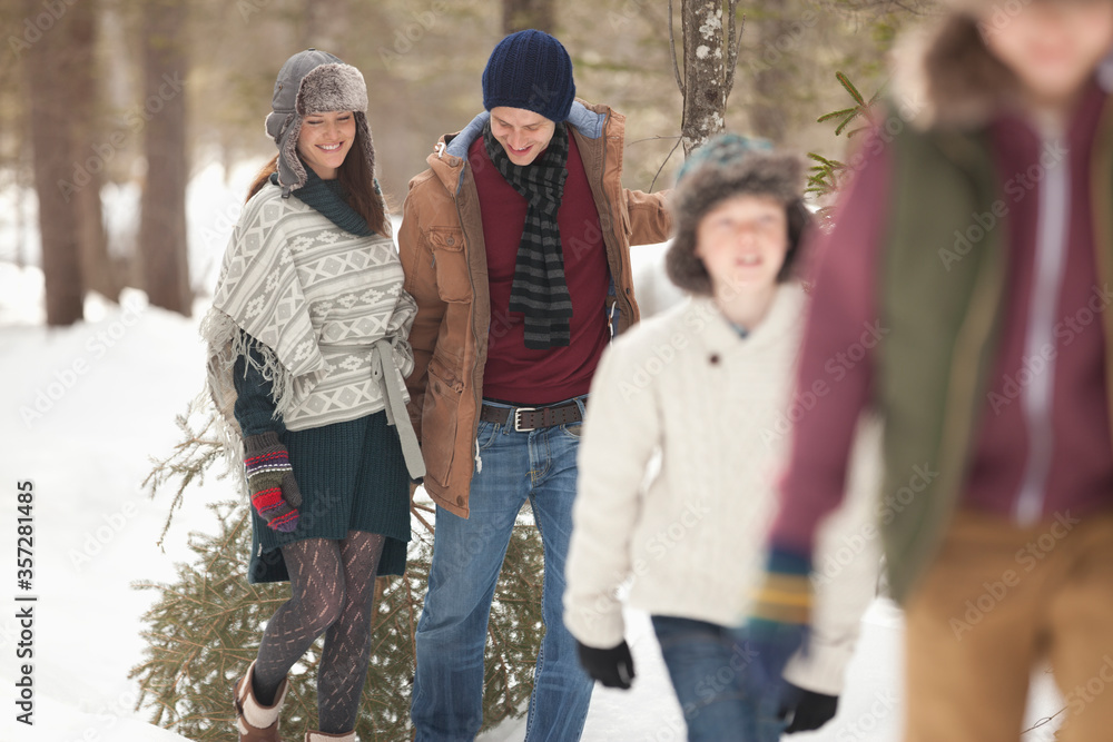 Happy family dragging fresh Christmas tree in snowy woods Happy family dragging fresh Christmas tree in snowy woods