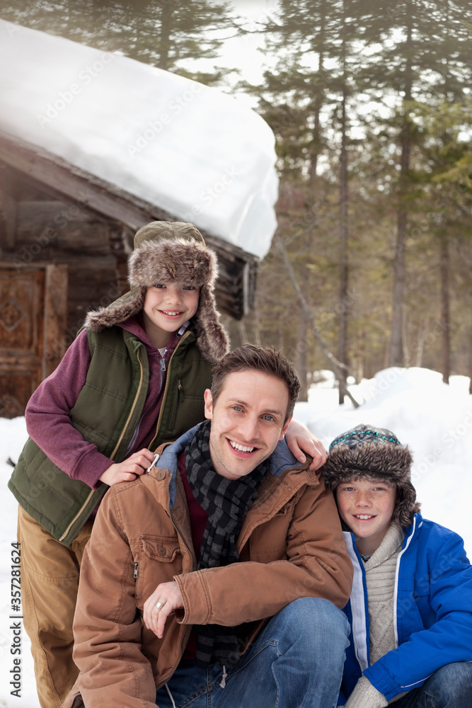 Portrait of smiling father and sons in snow outside cabin Portrait of smiling father and sons in snow outside cabin