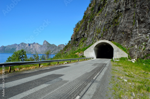 mountain tunnel opening with sea and mountain range in background