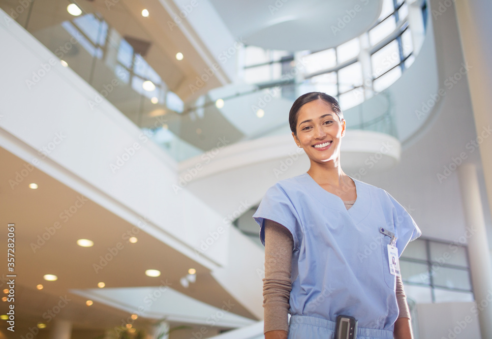Portrait of smiling nurse in hospital atrium - obrazy, fototapety, plakaty 