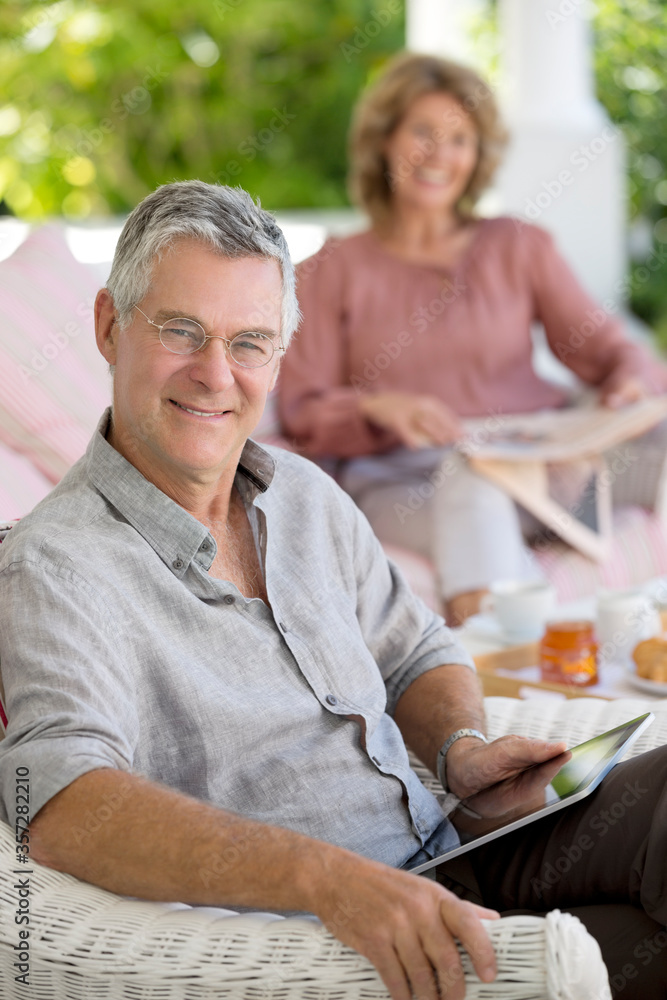 Senior man using digital tablet in armchair on patio Senior man using digital tablet in armchair on patio