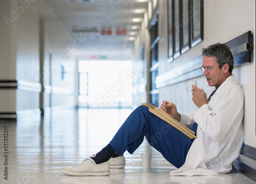 Doctor using dictaphone in hospital corridor photo