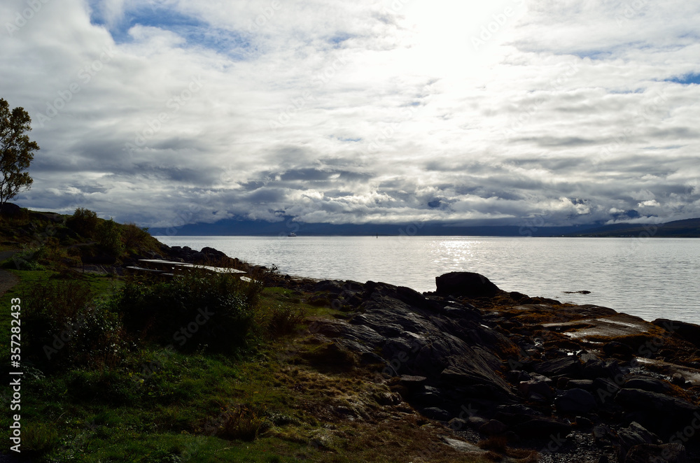 blue fjord, sunhine and thick clouds