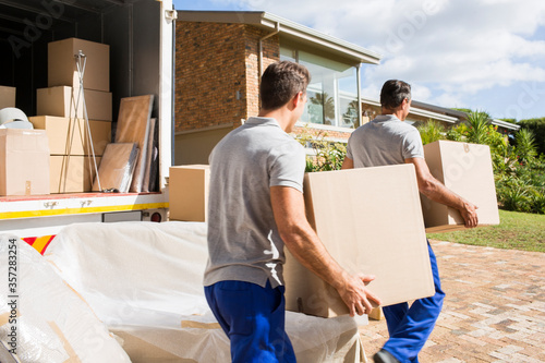Movers carrying boxes in new house