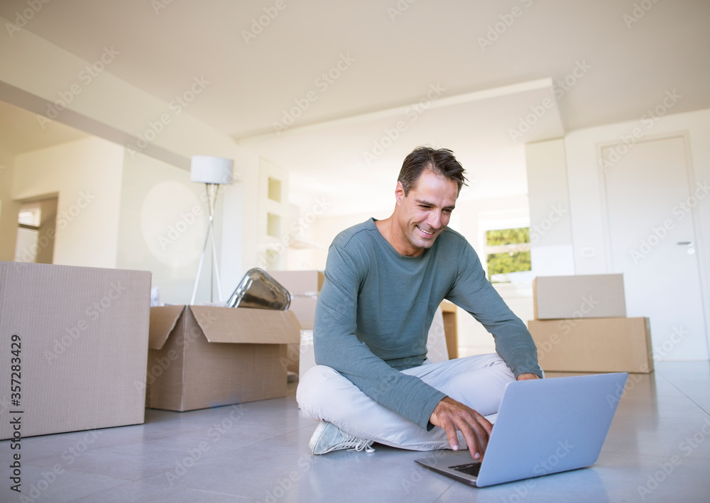 Man using laptop on floor among cardboard boxes Man using laptop on floor among cardboard boxes