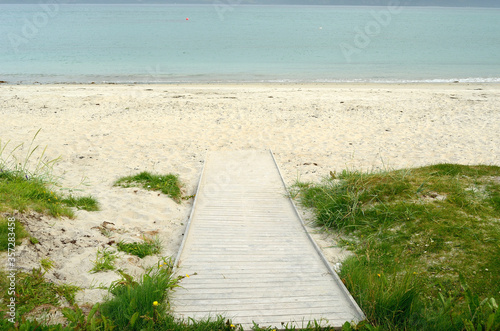 wooden walkway leading down to white summer beach sand