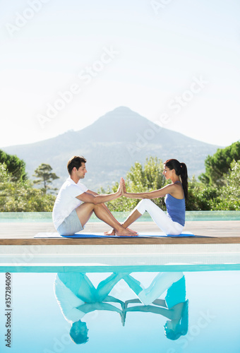 Couple practicing yoga poolside