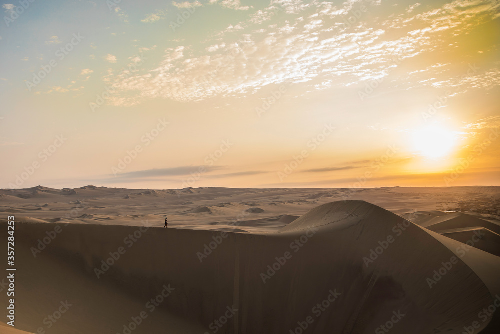 woman walking in the top of a dune and beautiful sunset