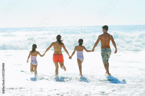 Family running into surf at beach