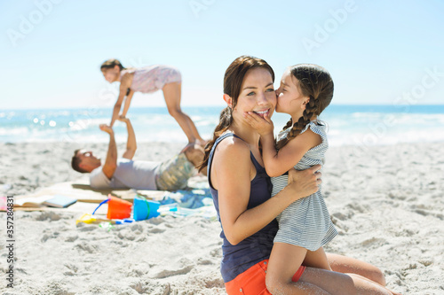 Girl kissing mother's cheek at beach