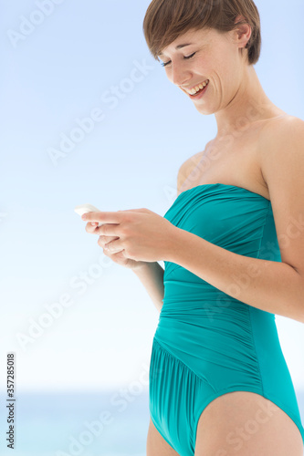 Woman in bathing suit using cell phone