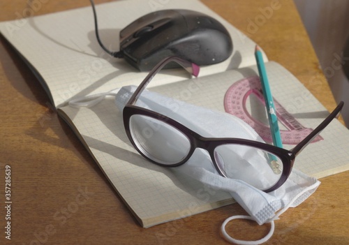 On the notebook is a medical mask, glasses, protractor, pen. Concept - protection from coronavirus, self-isolation mode, distance learning