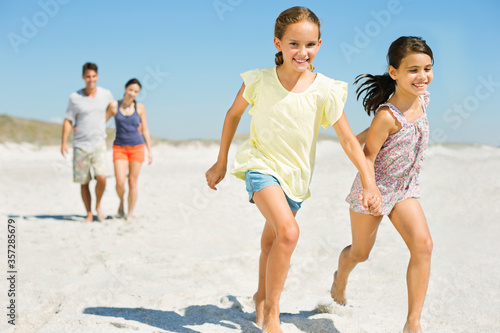 Girls holding hands and running on beach