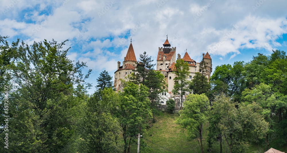 Bran or Dracula Castle under blue cloudy sky, panoramic view from Bran village in Transylvania, Romania