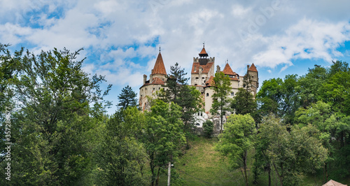 Bran or Dracula Castle under blue cloudy sky, panoramic view from Bran village in Transylvania, Romania