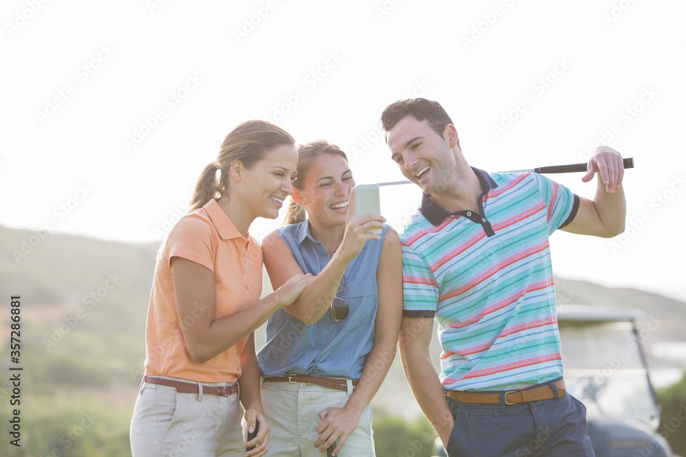 Friends looking at cell phone on golf course