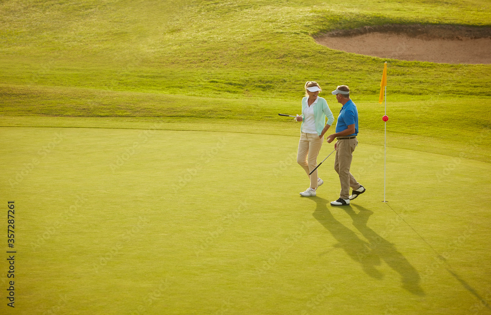 Obraz premium Senior couple walking on golf course