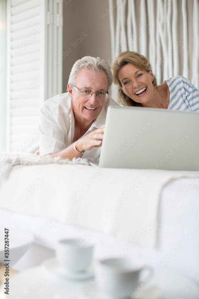 Older couple using laptop on bed