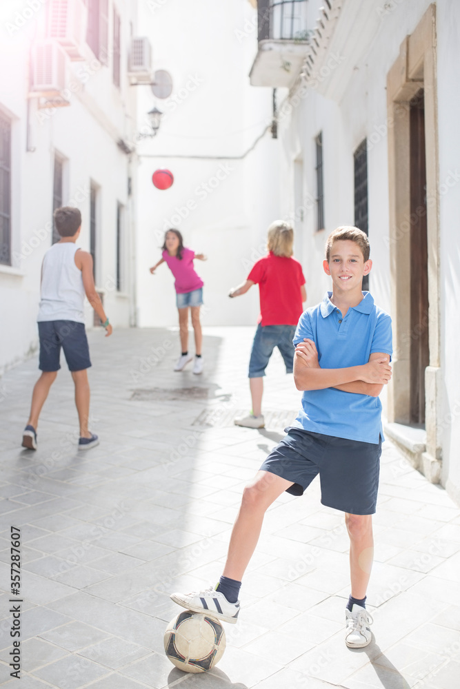 Boy holding soccer ball in alley