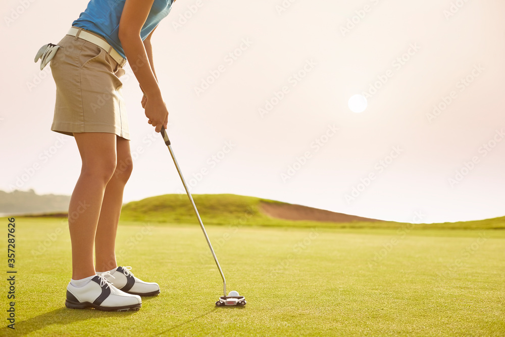 Fototapeta premium Woman putting on golf course