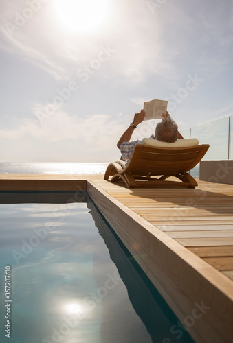 Man reading in lawn chair by pool