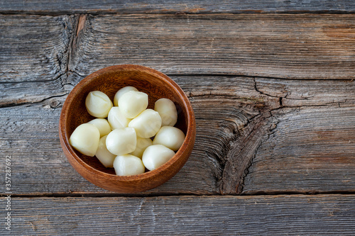 Scamorza cheese in a bowl on a wooden background.