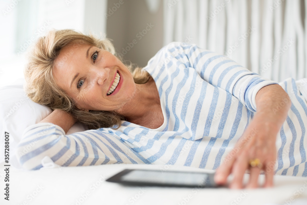Fototapeta premium Older woman using digital tablet on bed