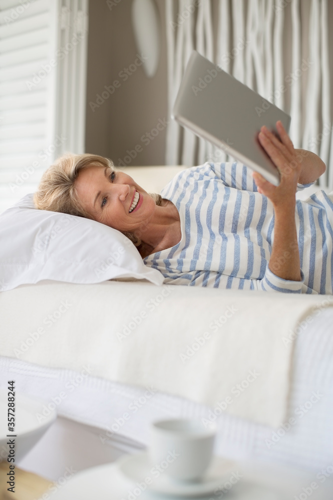 Older woman using digital tablet on bed Older woman using digital tablet on bed