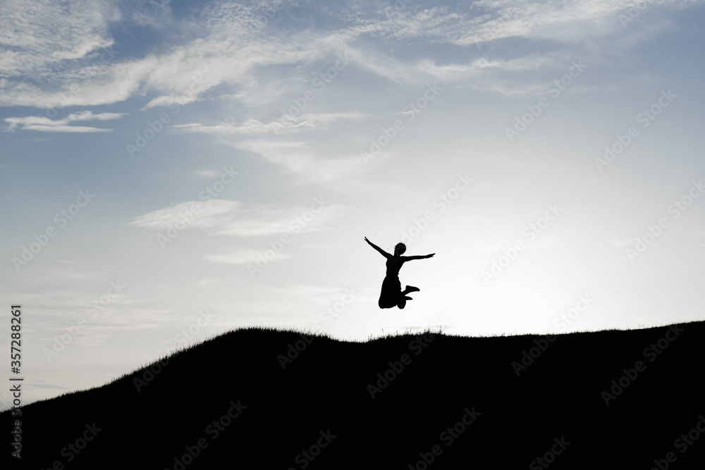 Happy woman jumping against beautiful sunset. Freedom, enjoyment concept. High quality photo