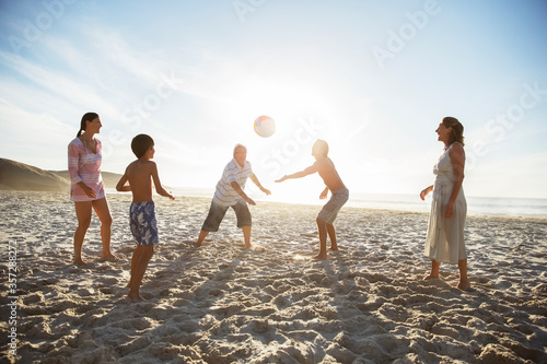 Multi-generation family playing volleyball on beach