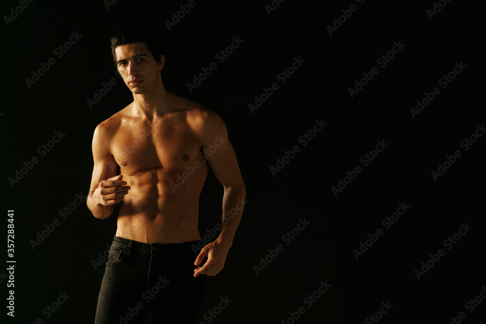 Horizontal view of a strong man with bare torso showing six pack abs, over black background.