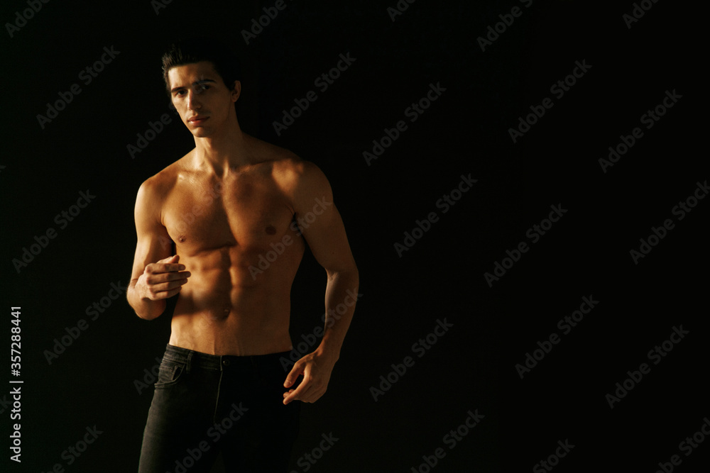 Horizontal view of a strong man with bare torso showing six pack abs, over black background. Horizontal view of a strong man with bare torso showing six pack abs, over black background.