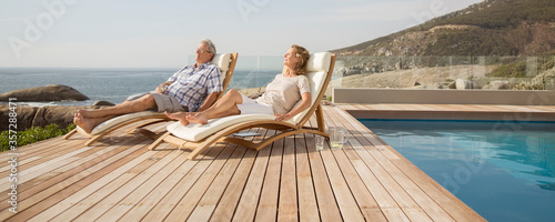 Canvas-taulu Older couple relaxing in lawn chairs by pool