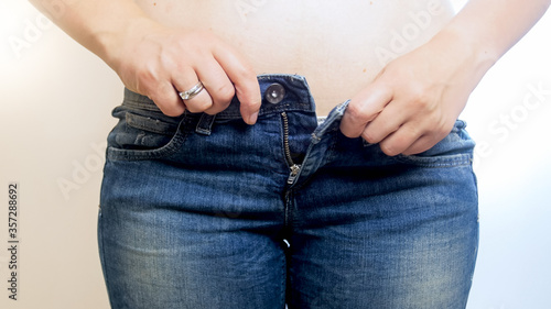 Young woman trying to button tight jeans
