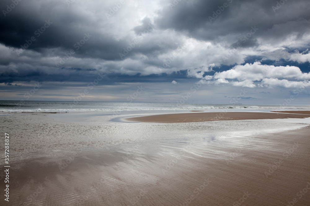 Obraz premium Clouds over beach at low tide