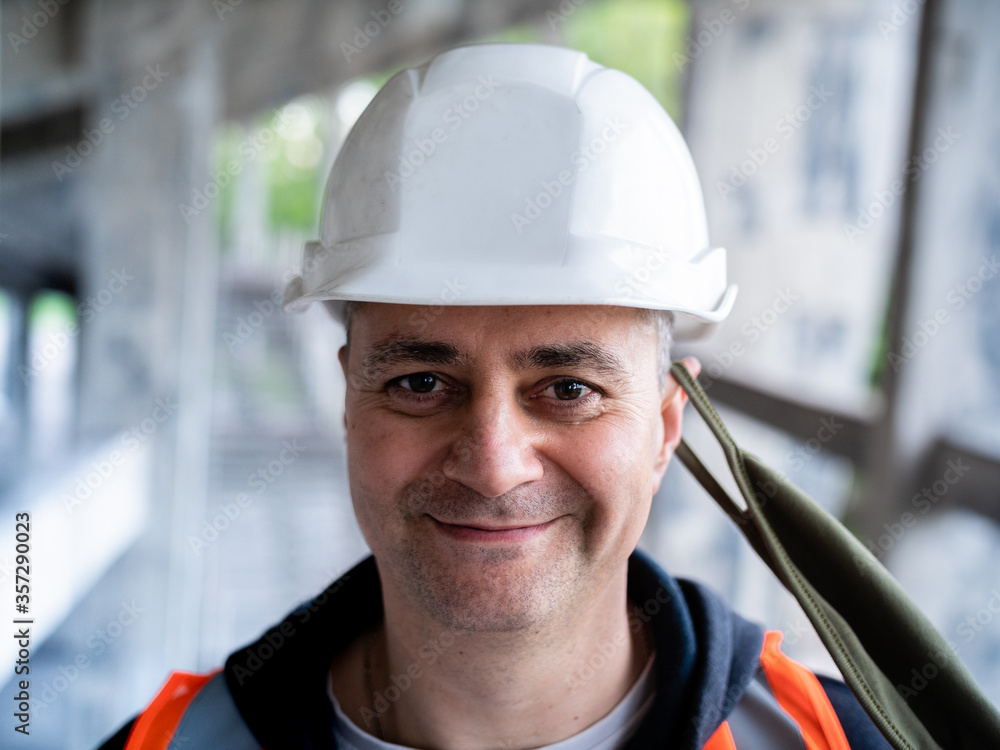 The man removes the protective mask from his face to symbolize the end of the pandemic. Portrait of a male Builder in a construction helmet and a medical antiviral mask. The man removes the protective mask from his face to symbolize the end of the pandemic. Portrait of a male Builder in a construction helmet and a medical antiviral mask.
