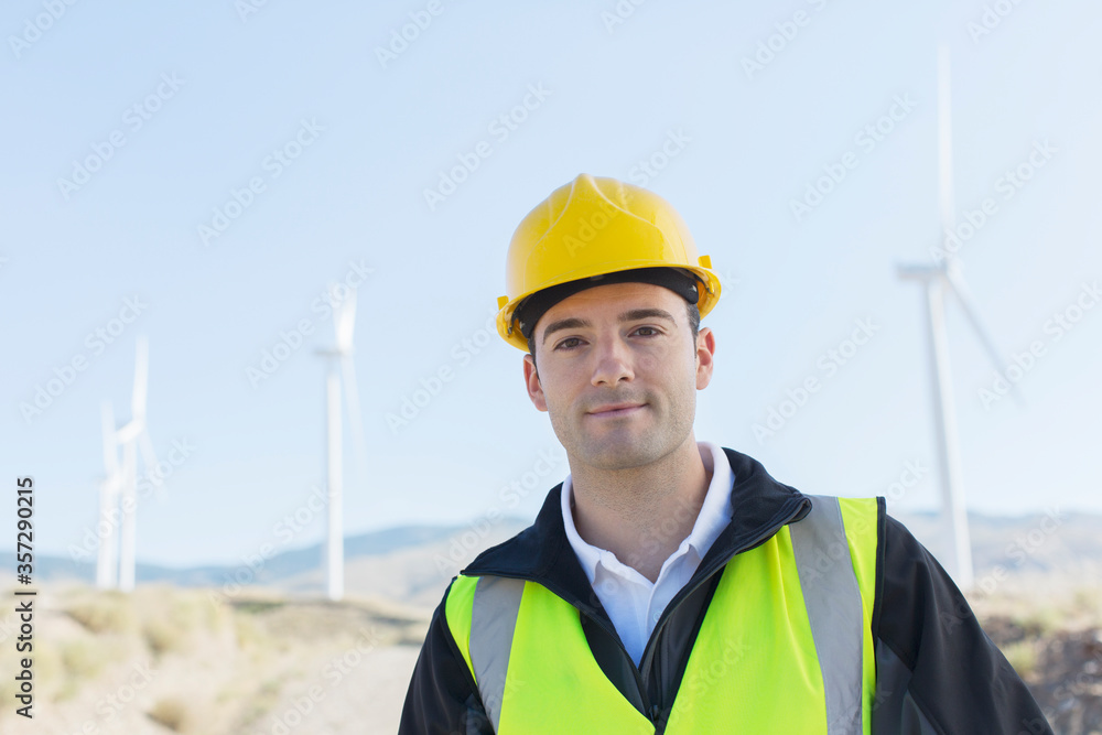 Worker standing by wind turbines in rural landscape Worker standing by wind turbines in rural landscape